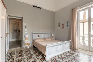 a white bedroom with a bed and a window at MAG guest house in Palermo