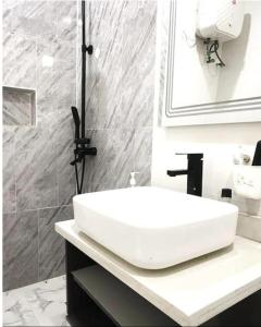 y baño con lavabo blanco y ducha. en Luxurious 2 bedroom Apartment with Private Chef en Lagos
