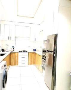 a kitchen with white cabinets and a stainless steel refrigerator at Luxurious 2 bedroom Apartment with Private Chef in Lagos