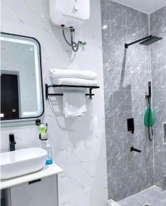 y baño blanco con lavabo y ducha. en Luxurious 2 bedroom Apartment with Private Chef en Lagos
