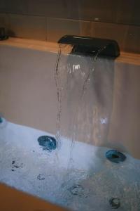 a bath tub with water coming out of a faucet at Ultimate Comfort ! Jacuzzi & Sauna. in Besançon