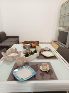 a living room with a table with dishes and a tv at La Rizzaia casa indipendente in Trapani