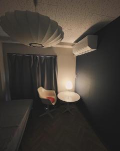 una camera con tavolo, sedia e lampada di Hostel UND BASE a Saiki