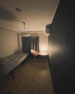 a room with a bed and a table and a chair at Hostel UND BASE in Saiki