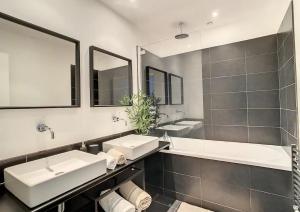 a bathroom with two sinks and two mirrors at Appartement Biarritz Saint Charles in Biarritz