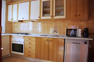 a kitchen with wooden cabinets and a sink and a microwave at Duplex Antonio Machado in Carboneras