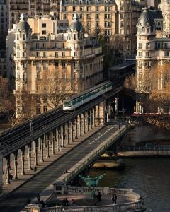 um comboio a atravessar uma ponte sobre um rio com edifícios em Studio 25m indépendant Tour Eiffel em Paris