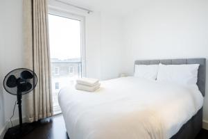 a bedroom with a large white bed with a window at Dreamwise apartment in Woolwich
