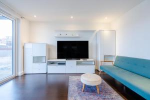 a living room with a blue couch and a tv at Dreamwise apartment in Woolwich