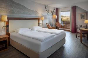 a bedroom with a large white bed and a desk at Arabella Jagdhof Resort am Fuschlsee, a Tribute Portfolio Hotel in Hof bei Salzburg