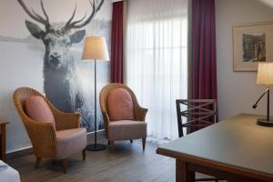 a hotel room with a desk and chairs and a deer mural at Arabella Jagdhof Resort am Fuschlsee, a Tribute Portfolio Hotel in Hof bei Salzburg