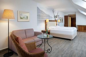 a living room with a bed and a couch and a table at Arabella Jagdhof Resort am Fuschlsee, a Tribute Portfolio Hotel in Hof bei Salzburg