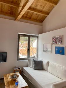 ein Wohnzimmer mit einem weißen Sofa und einem Fenster in der Unterkunft Rock Solid Stone House in Chora in Samothráki