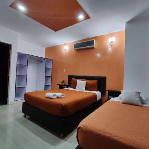 1 dormitorio con 2 camas con sábanas de color naranja en HOTEL MILLA SUITES MERIDA, en Mérida