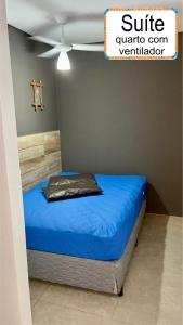a bedroom with a bed with blue sheets and a ceiling at Jardim do Mar suites in Ubatuba