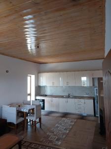 a kitchen with white cabinets and a table with chairs at Bert-House close to the sea in Lezhë