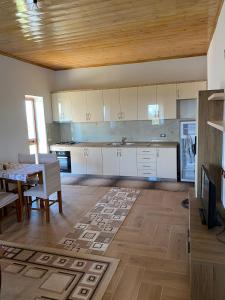 eine Küche mit weißen Schränken, einem Tisch und einem Esszimmer in der Unterkunft Bert-House close to the sea in Lezha