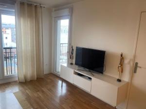 a living room with a television on a white cabinet at 3 pièces avec belle terrasse et vue dégagée. in Suresnes