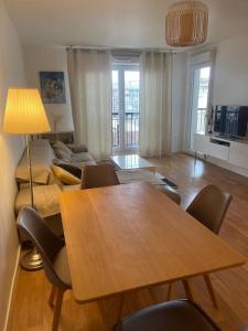 a living room with a table and chairs and a couch at 3 pièces avec belle terrasse et vue dégagée. in Suresnes