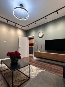 sala de estar con TV, mesa y reloj en Amazon House 8 en Tirana