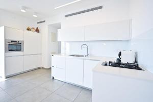 uma cozinha branca com armários brancos e um lavatório em Yellow blue by HolyGuest em Tel Aviv