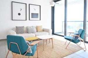 een woonkamer met een bank, stoelen en een tafel bij Yellow blue by HolyGuest in Tel Aviv