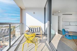 ein Wohnzimmer mit einem gelben Stuhl und einem Balkon in der Unterkunft Yellow blue by HolyGuest in Tel Aviv