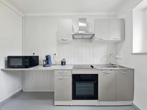 a white kitchen with a sink and a microwave at Appartement 2 chambres aux pieds des Vosges in Abreschviller