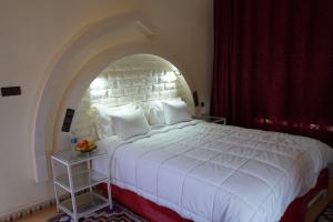 a bedroom with a large white bed with a brick wall at Riad Zagora Palms in Zagora