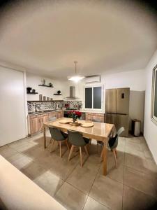 a kitchen with a wooden table and chairs in it at Les jardins de funtanone T4 in Vignale