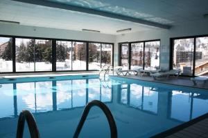 a large swimming pool with chairs and windows at Résidence Le Hameau Du Puy - Chalets pour 6 Personnes 874 in Le Dévoluy