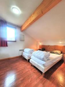 two beds in a room with a wooden floor at Résidence Le Hameau Du Puy - Chalets pour 6 Personnes 874 in Le Dévoluy