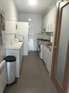 a small white kitchen with a washer and dryer at Piso con plaza de garaje y jardín in Cangas de Onís