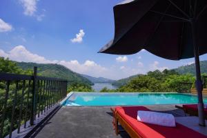 a pool with an umbrella and a view of the water at Victoria Hideout in Digana