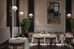 un restaurante con mesas y sillas blancas y un espejo en Sanasaryan Han, a Luxury Collection Hotel, Istanbul en Estambul