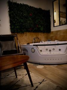 uma banheira branca numa sala de estar com uma cadeira em Maison Prestige Le Donjon des Plaisirs Jacuzzi em Montluel