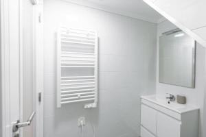 La salle de bains blanche est pourvue d'un lavabo et d'un miroir. dans l'établissement Cozy Bohemian Flat - Mint, à Lisbonne