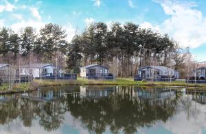 a group of cottages next to a lake at Hotchkin Lodge in Woodhall Spa