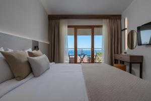 a bedroom with a bed with a view of the ocean at Alia Palace Hotel - Adults Only 16+ in Pefkochori