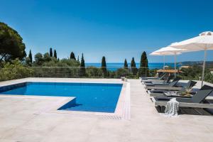 a swimming pool with lounge chairs and an umbrella at Escape Villa Kefalonia in Lourdhata