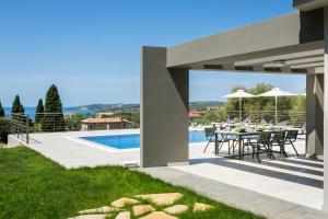 un patio con mesa y sillas junto a una piscina en Escape Villa Kefalonia, en Lourdata