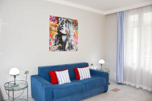 un sofá azul en una sala de estar con una pintura en la pared en Apt. 123 - Beautiful apartment on the lake en Porto Ceresio