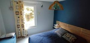 a blue bedroom with a bed and a window at Grande maison au charme chaleureux hiver comme été in La Bourboule