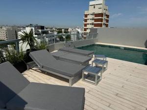 a patio with lounge chairs and a pool on a rooftop at Penthouse 100m2 Piscina Gym Parrilla Salon de Eventos Cochera Apertura 2024 in Buenos Aires