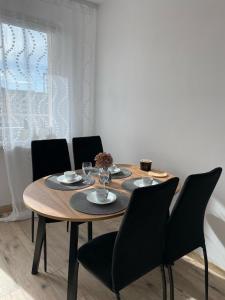 uma mesa de jantar com cadeiras pretas e uma mesa de madeira em Apartament Kasia em Wałbrzych