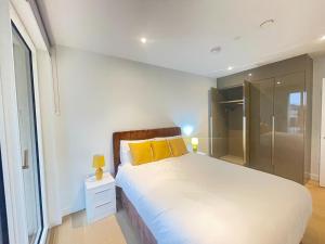 a bedroom with a large bed with yellow pillows at Large 2 Bed Apartment London Close to Lewisham Hospital - Perfect for Long Stay in London