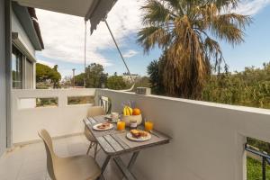 un balcón con mesa, sillas y una palmera en Erofili's Apartment Rhodes 10 minutes from beach, en Ialisos