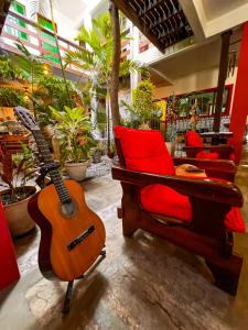 une guitare et une chaise dans une pièce ornée de plantes dans l'établissement Pousada Estalagem do Porto, à Arraial do Cabo