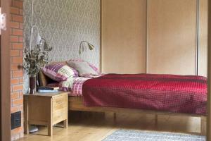 a bedroom with a bed with a red comforter and a table at Your getaway home in Jausa küla in Hiiumaa