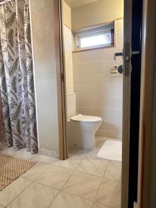 a bathroom with a toilet and a shower curtain at Your getaway home in Jausa küla in Hiiumaa